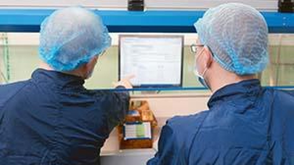 Two students looking at a screen with there back to the camera. One of them is pointing to the screen
