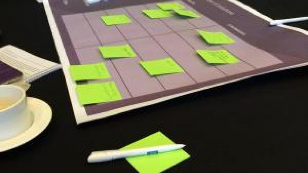 Green post it notes spread across a table on top of a scheduling poster 