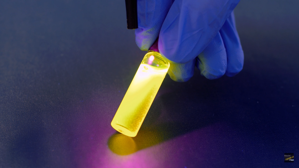 A small tube of glowing liquid, held by a gloved hand