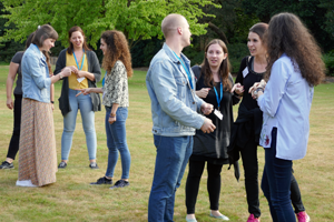 Two groups of students in conversation standing on grass 