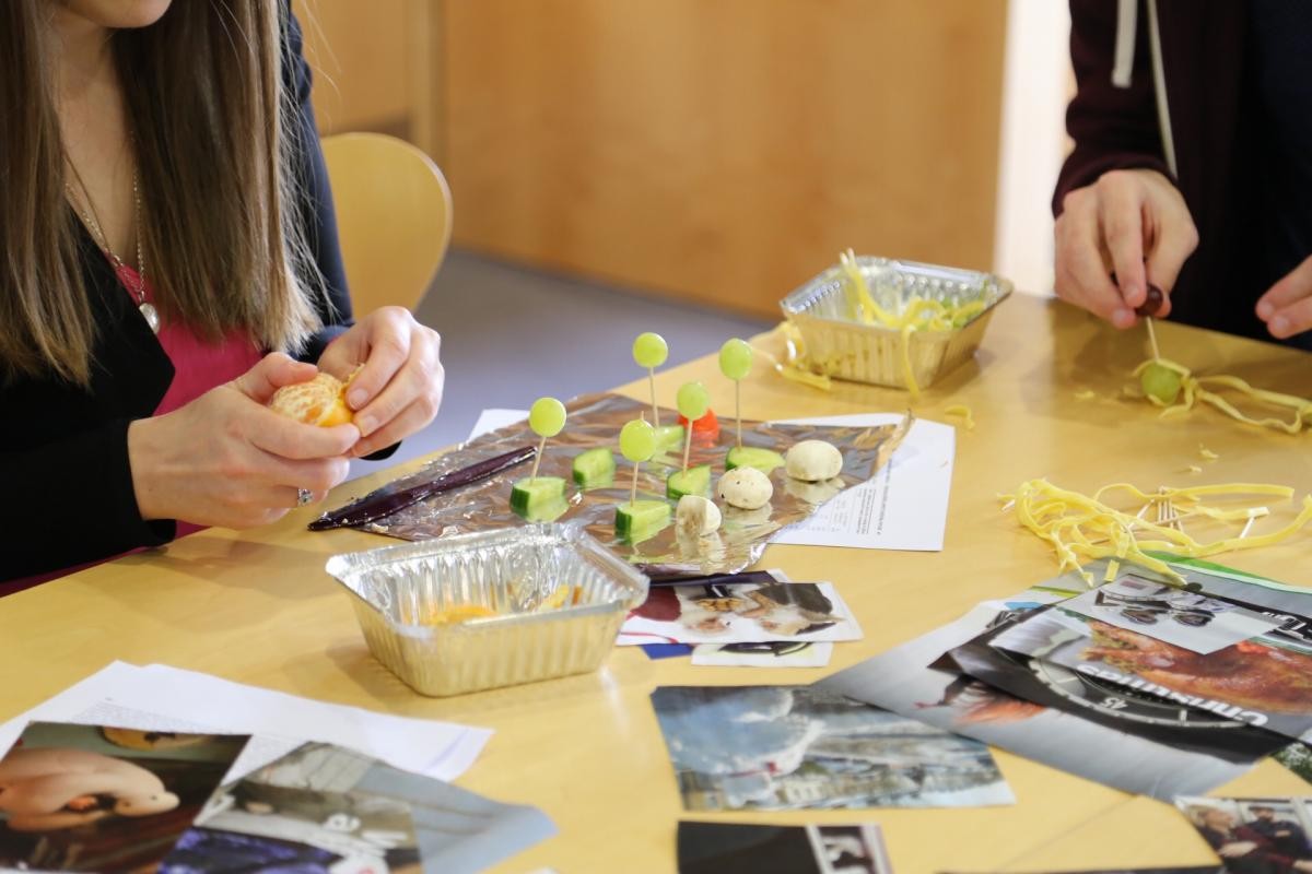 Two students partaking in a public engagement exercise. The students were challenged to present their research using only pictures from magazines, and then using food