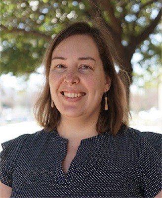 A headshot of Dr Lisa Wagar. She has shoulder length brown hair, is wearing a dark blue blouse and smiling at the camera.