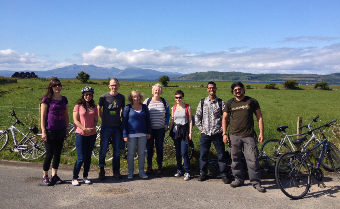 A group of researchers stand smiling on a sunny day after having paused on a bike ride.