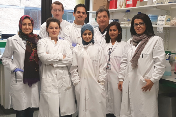 Dr Abdolrahman Shams Nateri with seven colleagues in white lab coats