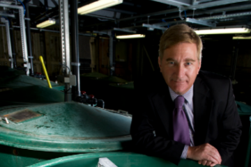 Professor Chris Secombes standing with a large green fish tank behind him