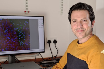 Grant holder David Fernandez-Antoran sitting at a computer displaying an image of cells.