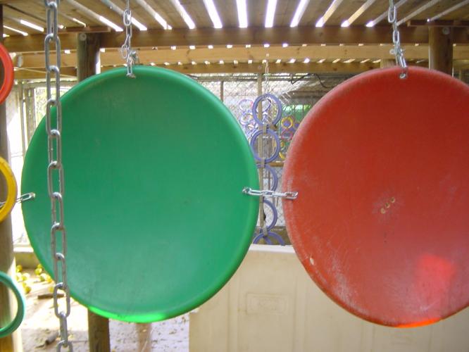 Two large plastic discs suspended from the ceiling of an enclosure. Vertical hanging items act as visual barriers enabling some privacy.