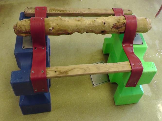 Two plastic horse jumps connected with three pieces of wood. This structural enrichment allows macaques to perch and hide within whilst also being manipulatable.